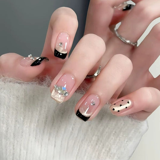 Hand wearing Midnight Spark black French and champagne glitter short square press-on nails with crystal accents